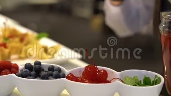糖果师把马拉西诺樱桃鸡尾酒樱桃放在一个小碗里旁边是蓝莓覆盆子和心叶视频的预览图