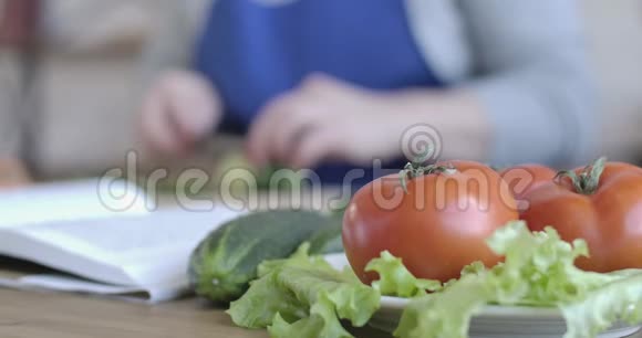 桌上摆放着新鲜有机蔬菜的特写镜头画面中女性用模糊的手切黄瓜视频的预览图