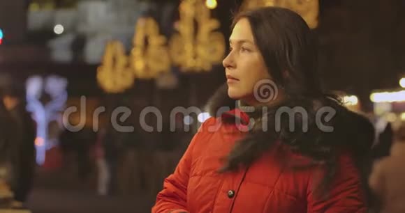 穿着红色外套的白种人成年女性的特写镜头看向侧面离开镜头中年黑发女士视频的预览图
