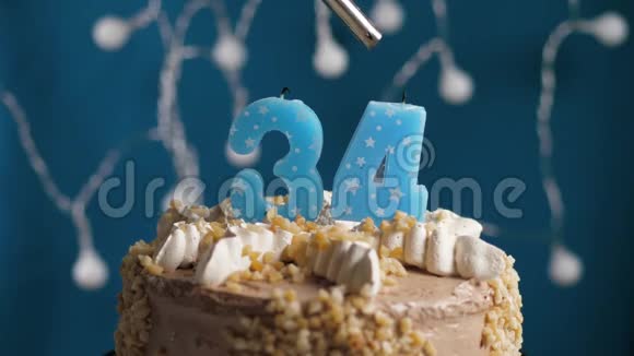 生日蛋糕蓝色背景上有34支蜡烛蜡烛吹灭了慢动作和特写视频的预览图