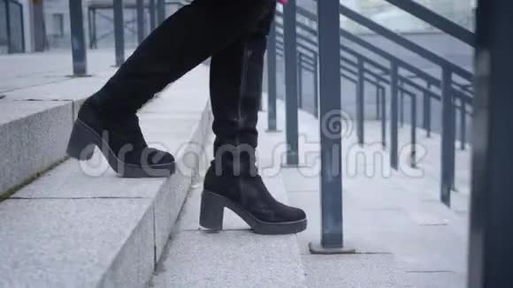 镜头跟随女腿穿着高靴走下楼梯女人在城里散步生活方式休闲视频的预览图