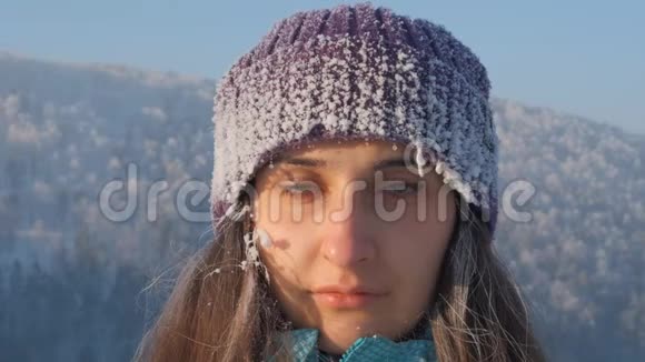 一个年轻迷人的冰冻女子在冬天的风景中微笑的慢镜头肖像视频的预览图