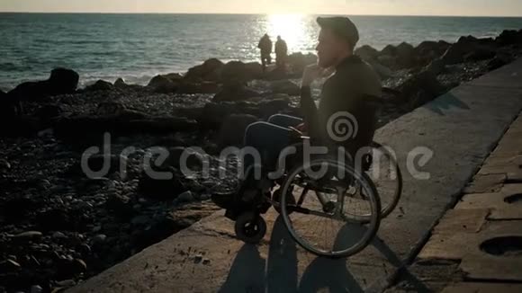 男性轮椅使用者在海上寻找在春天的傍晚思考视频的预览图