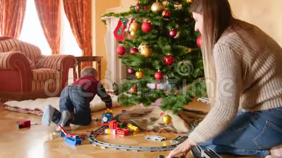 客厅圣诞树下幸福微笑家庭建造玩具铁路的4K视频接受礼物和礼物的儿童视频的预览图