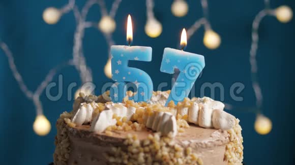 生日蛋糕与57号蜡烛和闪闪发光的蓝色背景慢速运动和特写镜头视频的预览图