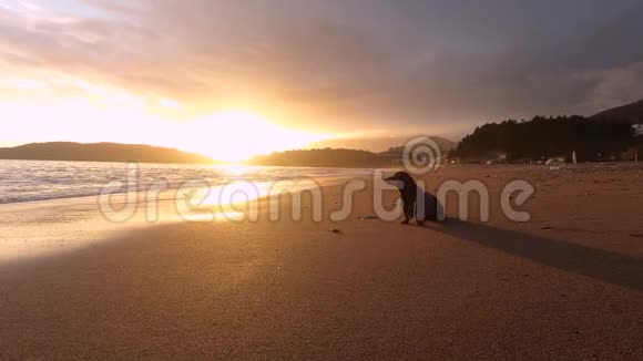 达春德穿着帽衫坐在海滩上山峦海景和炽热的黎明或日落视频的预览图
