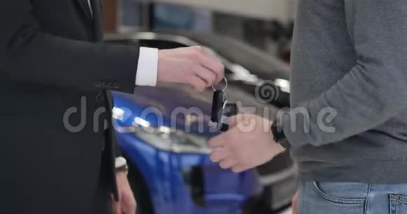 无法辨认的白种人男性客户拿着车钥匙从经销商和握手两个人在汽车经销店视频的预览图