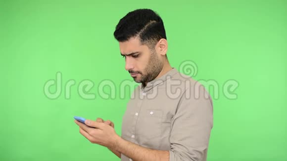 漂亮开朗的黑发男人用手机在社交网络上聊天变得惊讶色度键视频的预览图