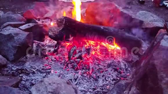 营火燃烧岩石中的木头燃烧着红色黄色和橙色的火焰视频的预览图