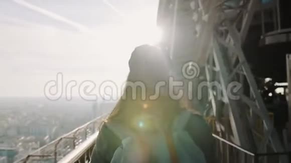 影院镜头耀斑拍摄年轻旅游女性漫步巴黎埃菲尔铁塔金属观景点上日落慢动作视频的预览图