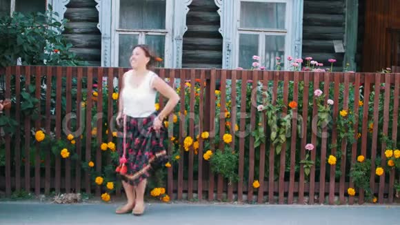一个穿着长裙的快乐女人在篱笆旁的街道上跳舞视频的预览图