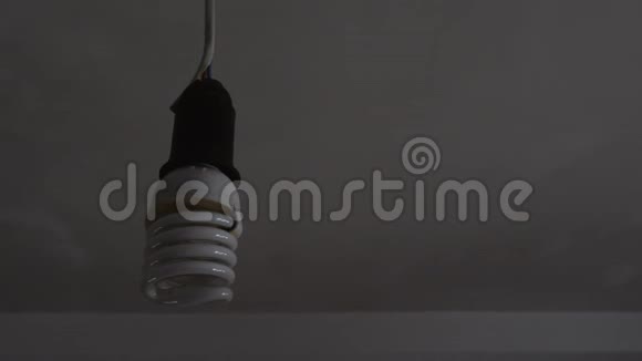 在一个黑暗的房间里一个女人用一盏新的LED了一盏节能灯视频的预览图
