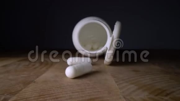 白色药丸或胶囊旁边的瓶子在木桌背景药品处方治疗用药制药视频的预览图
