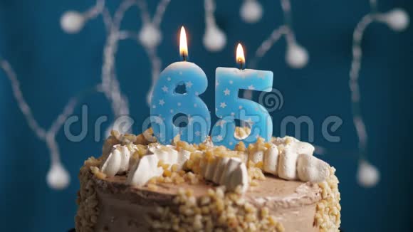 生日蛋糕上面有65个数字蜡烛在蓝色的背景上蜡烛吹灭了慢动作和特写视频的预览图
