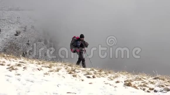 徒步旅行者背着背包走在山岭上覆盖着深深的雪视频的预览图