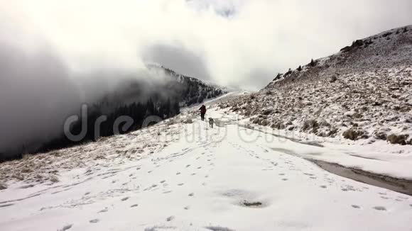 徒步旅行者背着背包走在山岭上覆盖着深深的雪视频的预览图