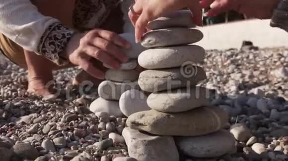 亲密的家庭手在海岸上折叠一个金字塔石视频的预览图