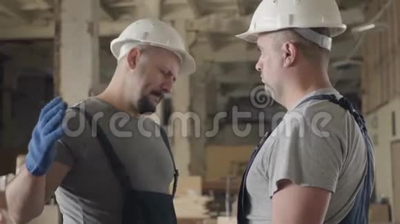 长胡子的白种人建筑工人肩膀上有纹身摇动着同事手微笑着两个人在视频的预览图