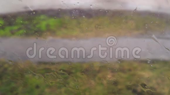刮风的街道上的雨天玻璃窗上的水滴视频的预览图