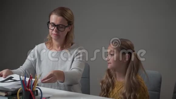 一位戴眼镜的白人年轻家庭教师的肖像向她的学生出示带有字母Z的卡片并解释正确的视频的预览图