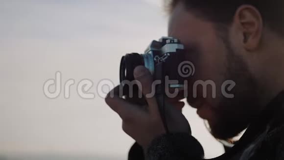 特写侧景的年轻快乐胡子创意摄影师男子拍照与老式电影相机慢镜头视频的预览图
