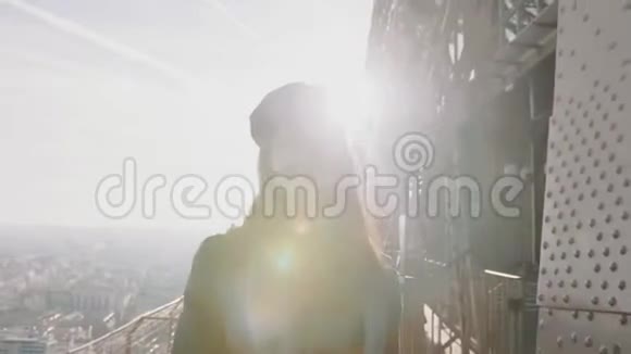 惊人的镜头耀斑拍摄年轻的旅游妇女走向相机微笑沿着埃菲尔铁塔顶部缓慢的运动视频的预览图