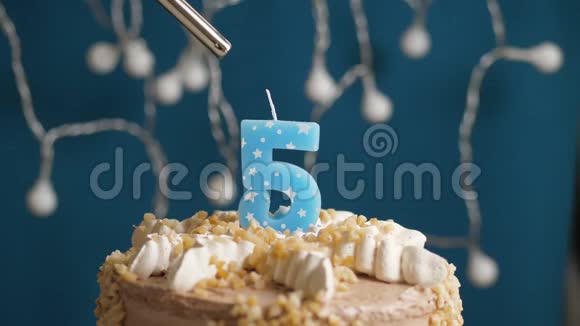 生日蛋糕与5号燃烧蜡烛由打火机在蓝色的背景蜡烛被点燃了慢速运动和特写镜头视频的预览图
