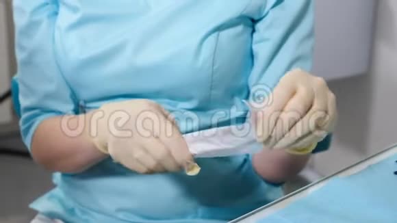 戴蓝色乳胶手套准备工作的女牙医特写镜头用牙科无菌工具打开工艺包视频的预览图