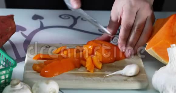 女人在厨房的木板上切橙胡椒女性手准备一份带有甜椒的沙拉健康视频的预览图
