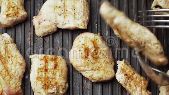 在家用电烤架上烹饪美味的烤肉猪肉的美味厨师用叉子把肉翻过来快关门顶部视图视频的预览图