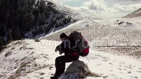 徒步旅行者背着背包走在山岭上覆盖着深深的雪视频的预览图