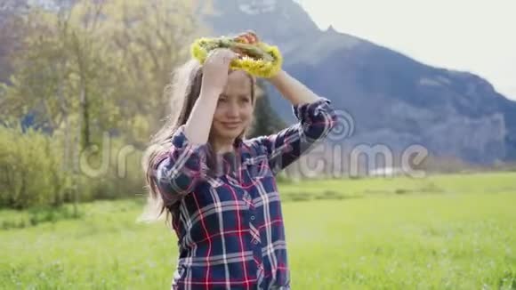 美丽幸福的女人在山上尝试蒲公英花环的肖像视频的预览图