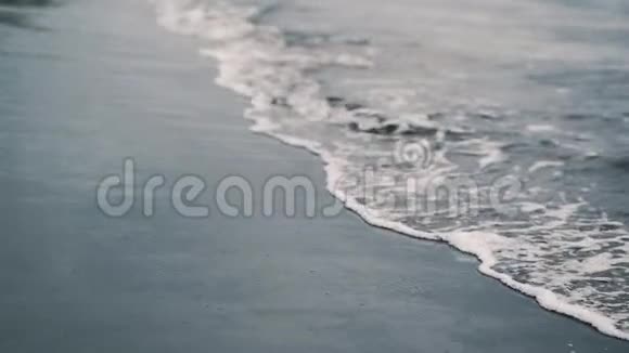 海浪撞击黑色火山沙飞溅和白色泡沫缓慢运动视频的预览图