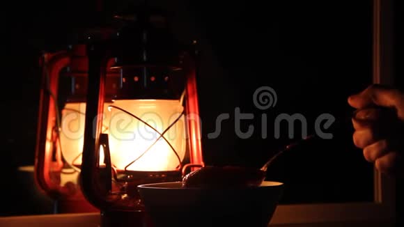 手拿一勺蜂蜜放在煤油灯的背景上视频的预览图