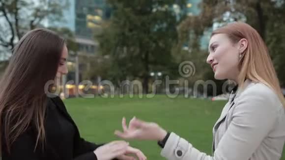 两个年轻漂亮的女孩在城市公园里聊天视频的预览图