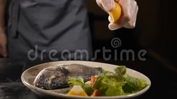 慢动作的食物镜头厨师挤压半切柠檬鱼有绿叶和柠檬的鱼视频的预览图
