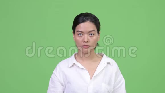 年轻漂亮的亚洲女人捂着嘴看着震惊视频的预览图
