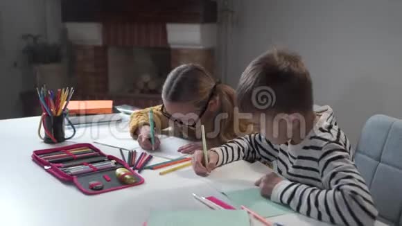 高加索兄妹一起做作业快乐的孩子在兄弟姐妹的练习本上写作穿条纹衣服的男孩视频的预览图