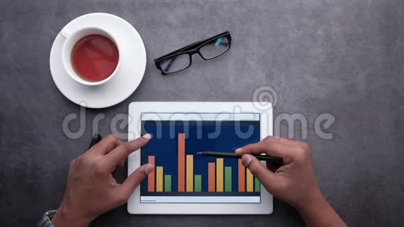办公桌数码平板电脑男子手分析条形图的俯视图视频的预览图