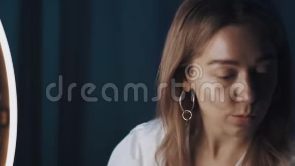 女视频博主坐在圈灯前手里拿着化妆品棒视频的预览图