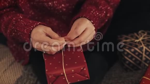紧紧抓住女人的手最后敲定圣诞红色礼物盒包扎胶带并绑在蝴蝶结假期及假期概念视频的预览图