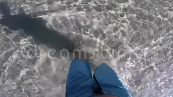 年轻男子的腿部特写镜头慢动作地走在海边的水晶水旁视频的预览图