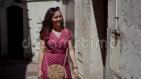 美丽的女人穿着红色的波尔卡多礼服沿着古老建筑的石墙散步浪漫的肖像视频的预览图