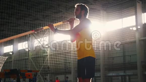 室内撑竿跳高一名身穿黄色衬衫的男子拿着撑竿站在跑道上准备跳高视频的预览图