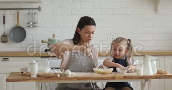 快乐的妈妈和小女儿在厨房里打面团视频的预览图
