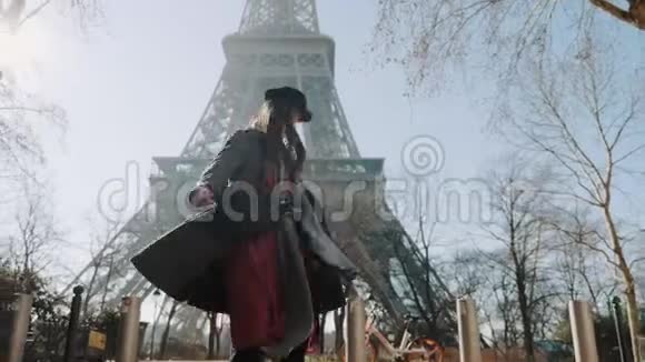 低角度美丽的快乐博客女性摆姿势欢快地旋转着张开双臂在巴黎埃菲尔铁塔缓慢的运动视频的预览图