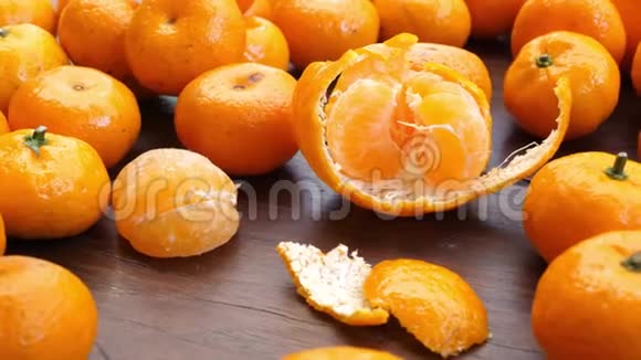在棕色的木桌上许多散落的橘子中间有一个去皮的水果视频的预览图