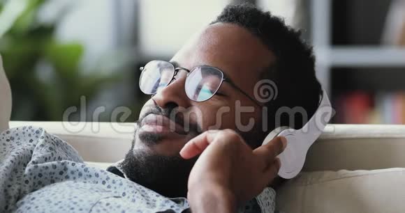 非洲男人戴耳机听音乐坐坐沙发视频的预览图