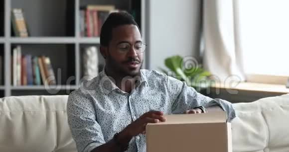 兴奋的非洲男性顾客在家中收到打开的包裹盒视频的预览图