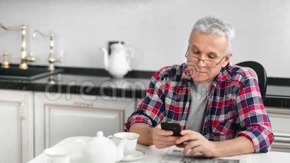 早餐时戴着智能手机眼镜的自信成熟的白发男子视频的预览图